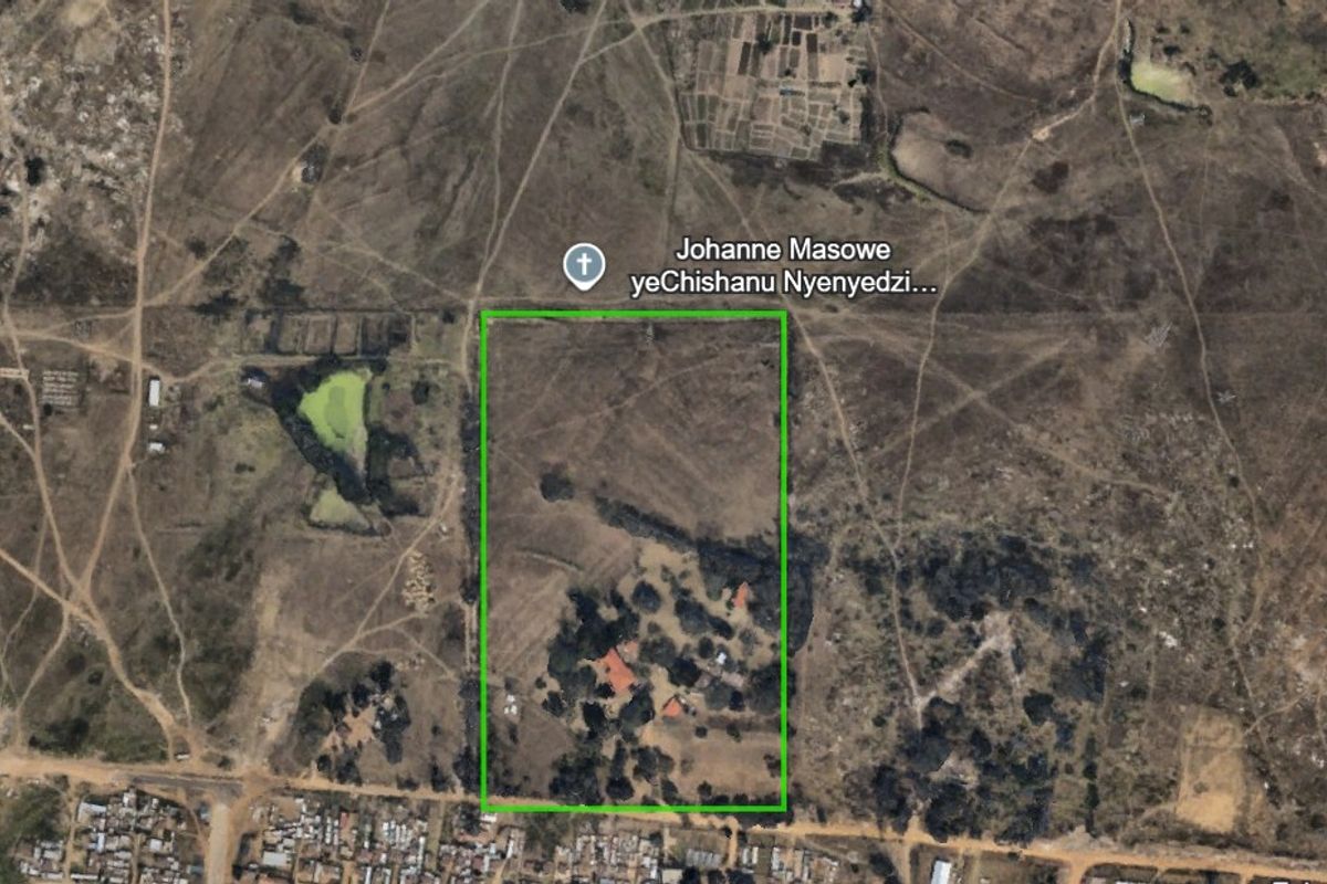 Aerial view of a farm property showing the land boundaries, surrounding landscape, and existing structures on the plot.
