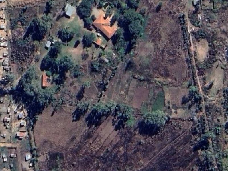 Aerial view of a large farm property featuring a main residence, multiple outbuildings, and extensive open land.