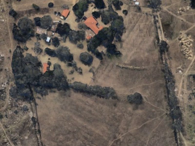 Aerial view of a large farm property featuring a main dwelling, several outbuildings, mature trees, and a fenced perimeter.