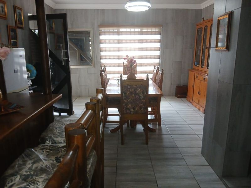 A dining area featuring tiled flooring, wall cladding, and a window with fitted blinds, providing a functional space for meals.