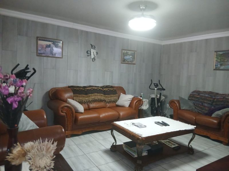 A living room featuring tiled flooring and grey wood-look wall paneling, providing a neutral base for the living space.