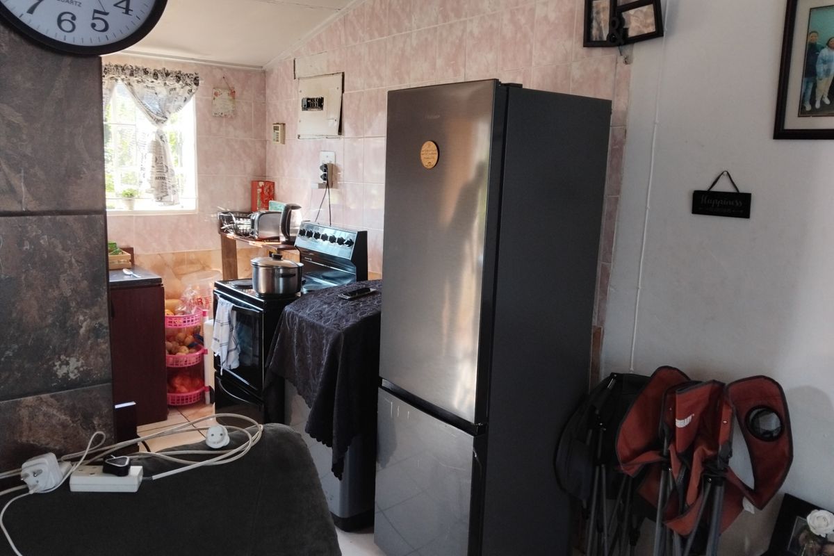 A functional kitchen area featuring tiled walls and a freestanding stove, offering potential for modernization and improved layout efficiency.