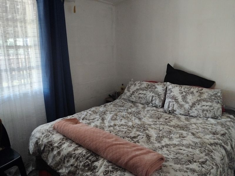 A standard bedroom featuring a window with curtains, providing natural light and a simple layout.
