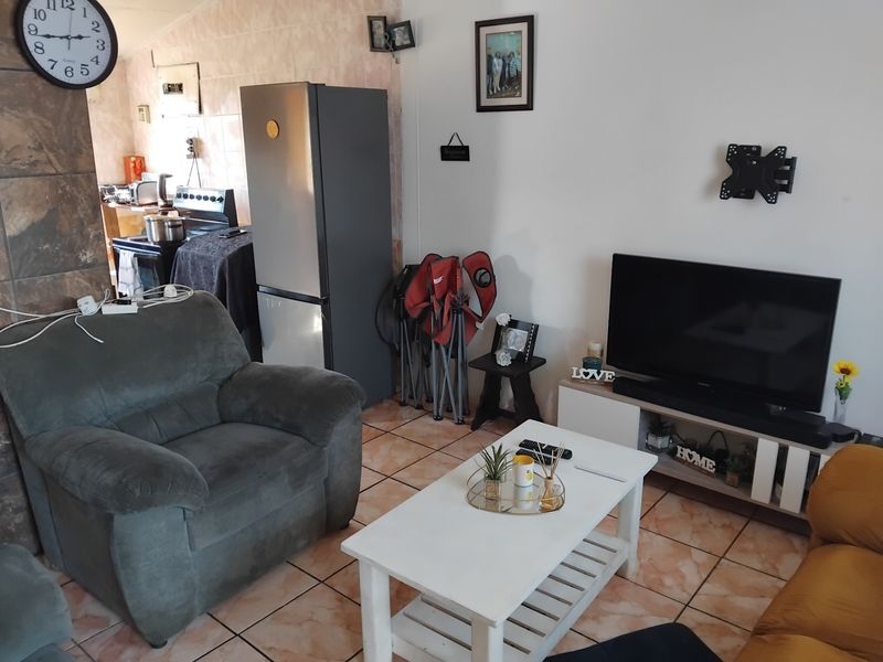 An open-plan living area featuring tiled flooring and a connected kitchen space, providing a functional layout for daily living.