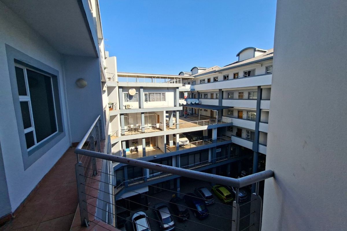 View from a balcony overlooking the central courtyard and parking area of a multi-story apartment complex.