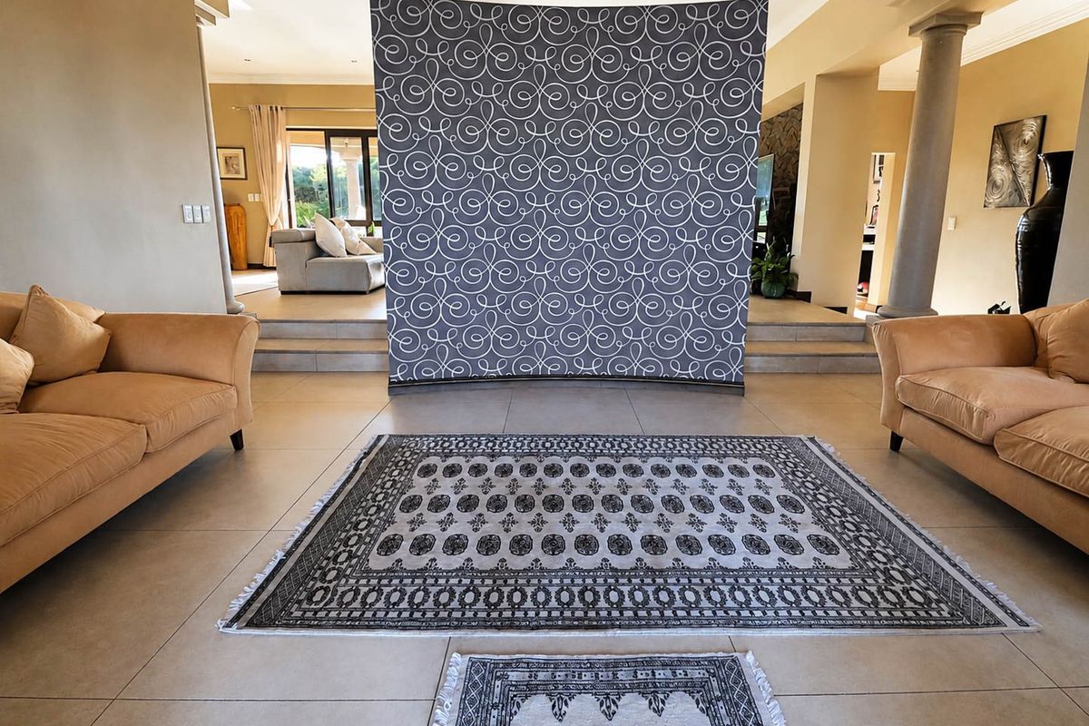 Spacious living area featuring large format floor tiles, decorative columns, and a raised platform level, creating a distinct open-plan layout.