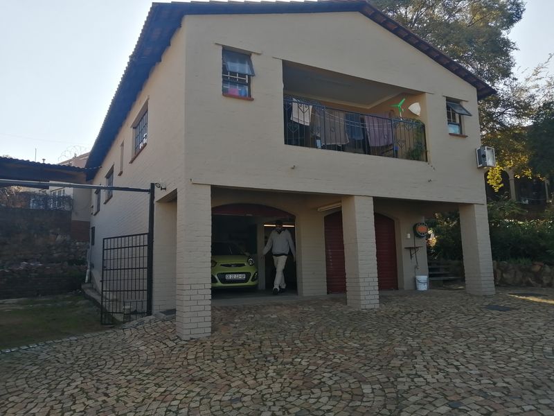 Two-story residential property featuring a double garage on the ground level and an upper-level balcony with brick paving in the driveway.