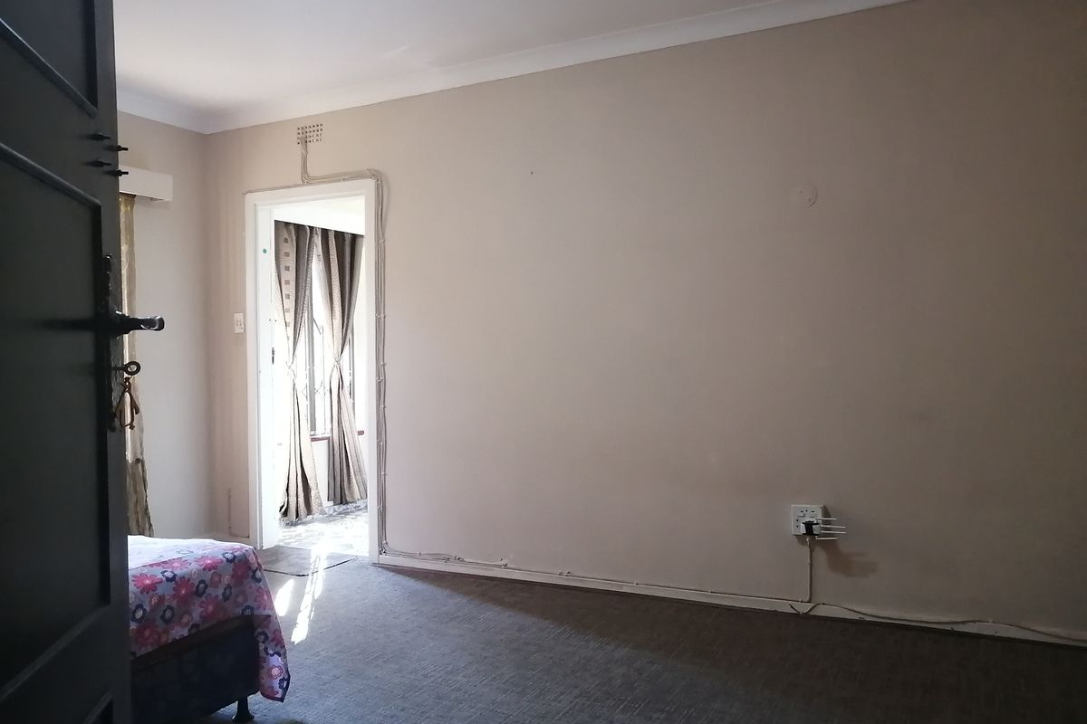 A bedroom featuring carpeted flooring and coved ceilings, with visible surface-mounted electrical conduit running along the wall.