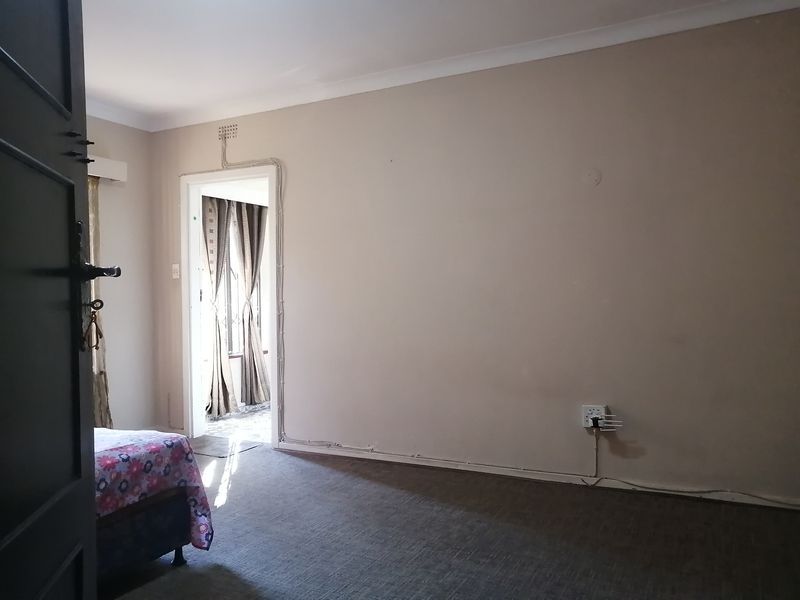 A bedroom featuring carpeted flooring and coved ceilings, with visible surface-mounted electrical conduit running along the wall.