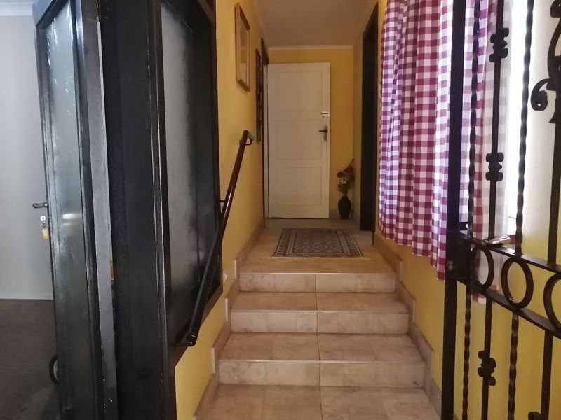 A functional hallway featuring a tiled staircase with a handrail, leading to an internal door, secured by a metal gate.