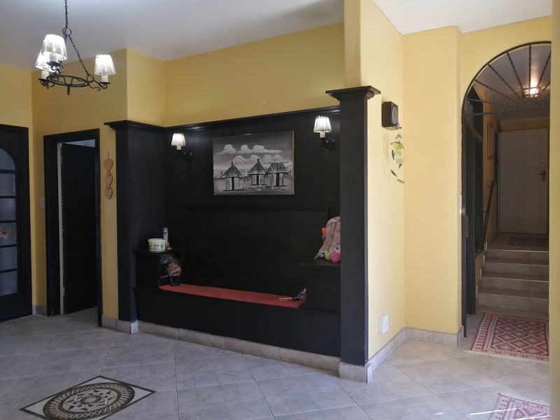 Spacious entrance hall featuring tiled flooring, a built-in bench with integrated lighting, and an arched doorway leading to a staircase.