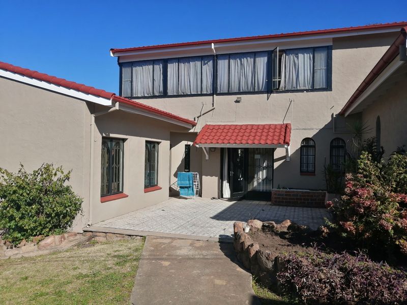 Rear exterior view of the house featuring a tiled patio area, stone garden borders, and a red tiled roof with security-fitted windows.