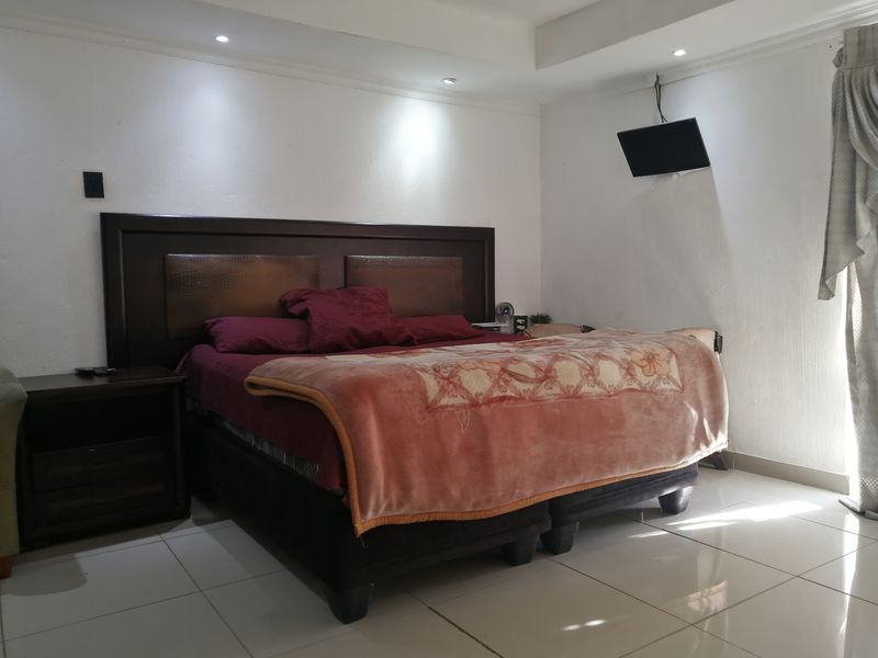 A well-lit bedroom featuring tiled flooring, recessed ceiling lighting, and a coved ceiling design, providing a clean and functional sleeping space.