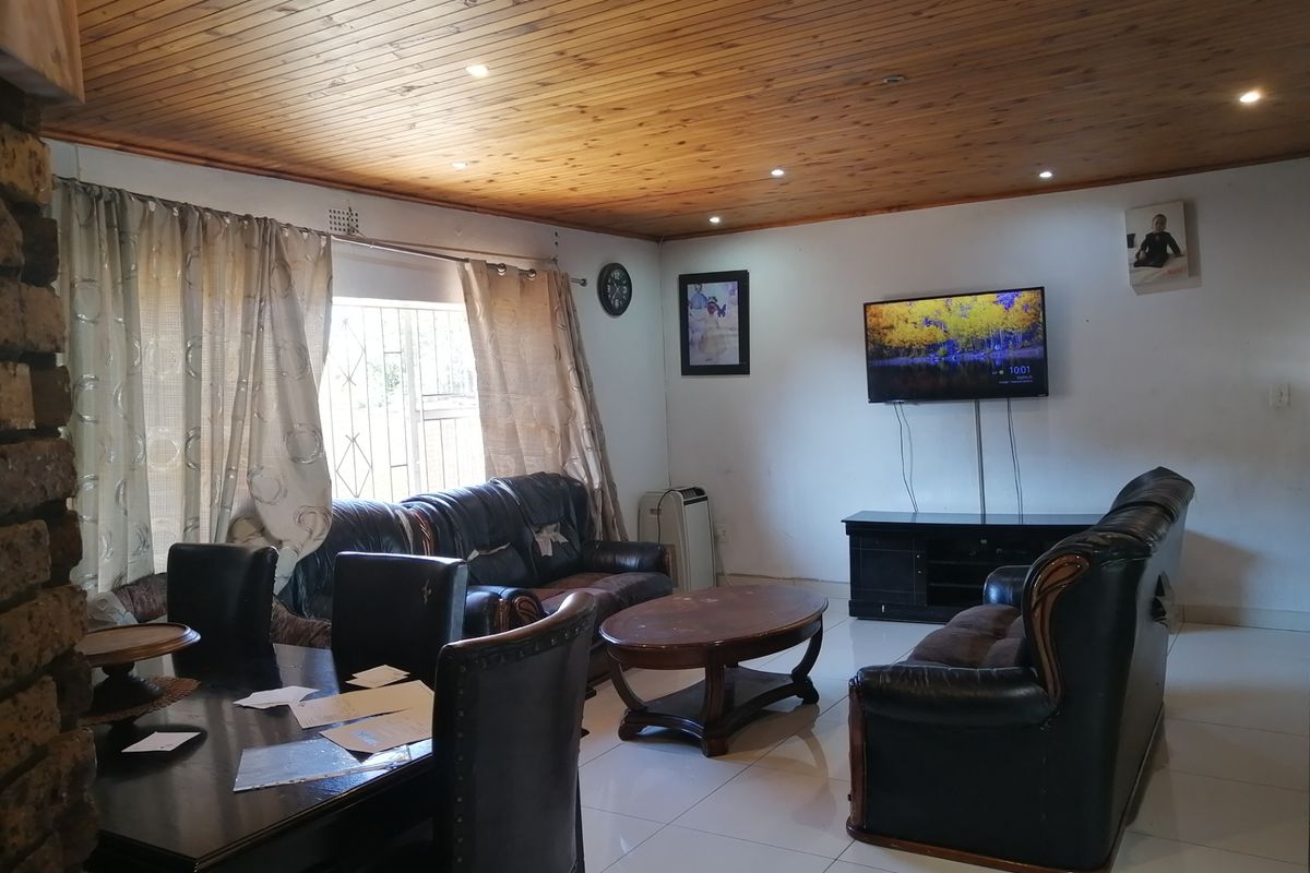 A living room featuring a timber tongue and groove ceiling, recessed downlights, and tiled flooring, providing a functional and lived-in space.