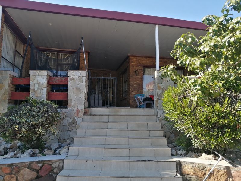 Front entrance featuring a tiled staircase leading to a covered patio with stone cladding and brick facade details.