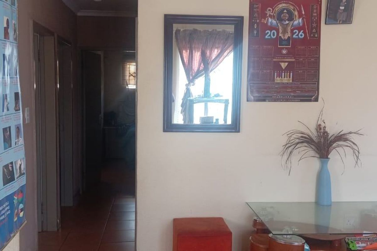 A view of a residential hallway with tiled flooring and access to adjacent rooms.