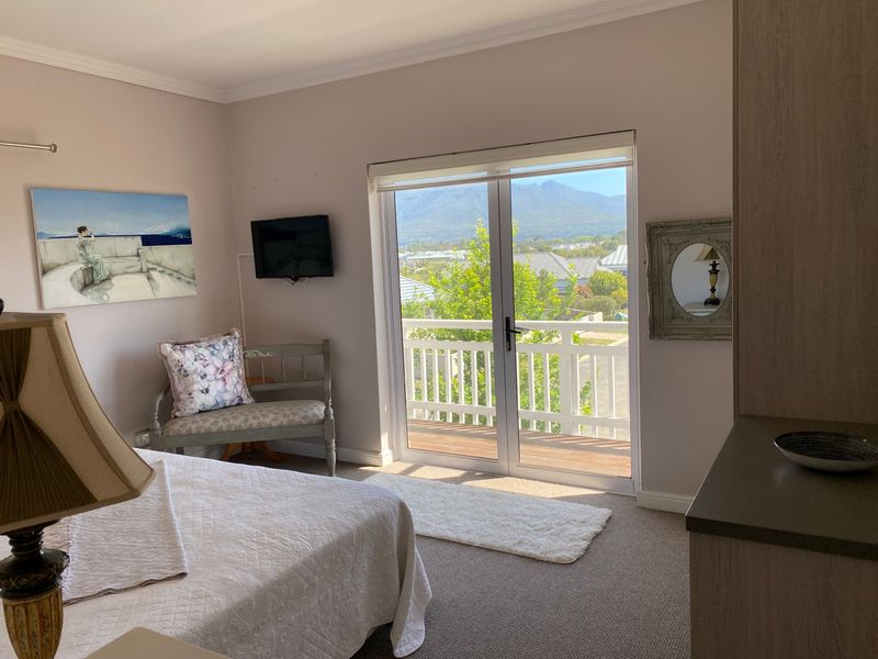 A well-maintained bedroom featuring carpet flooring, built-in cabinetry, and double glass doors opening onto a balcony with scenic mountain views.