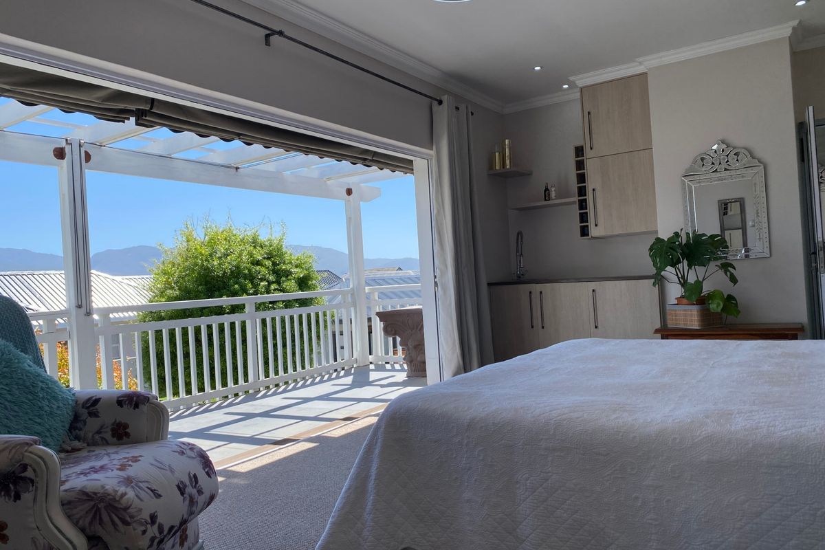 Spacious bedroom featuring built-in cabinetry with a sink, recessed lighting, and large sliding doors opening onto a covered patio with mountain views.