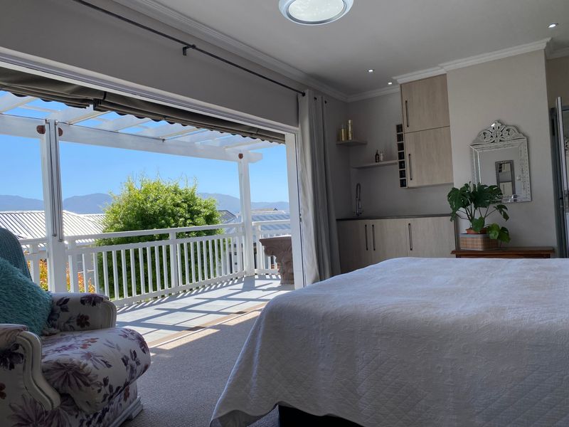 Spacious bedroom featuring built-in cabinetry with a sink, recessed lighting, and large sliding doors opening onto a covered patio with mountain views.