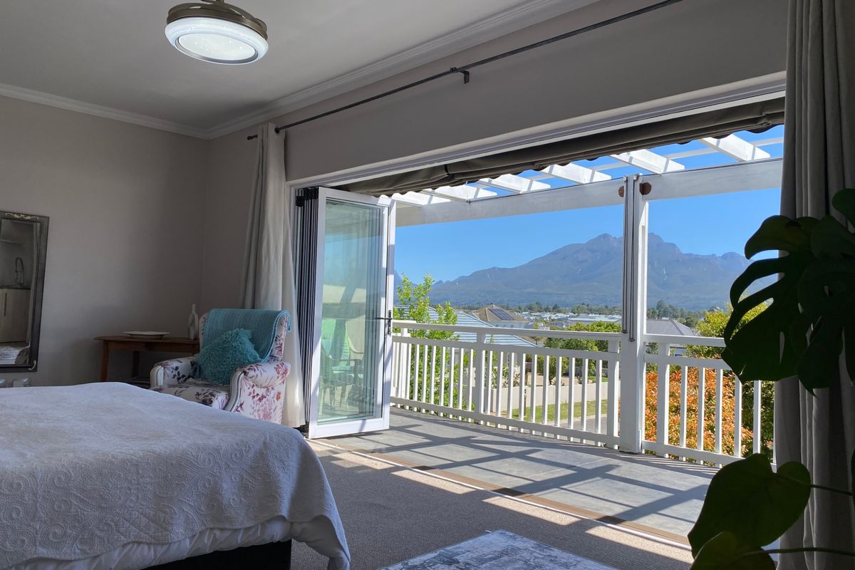 Spacious bedroom featuring large bi-fold doors opening onto a balcony with a pergola and scenic mountain views.
