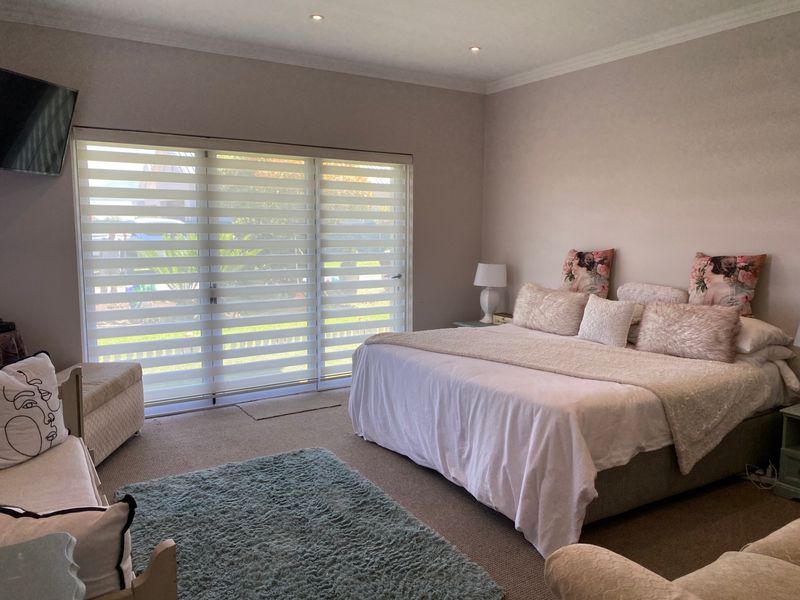 Spacious bedroom featuring large sliding glass doors with modern blinds, recessed ceiling lighting, and neutral carpeting.