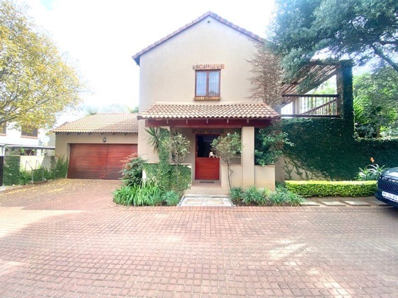 Front elevation of a two-story house featuring a paved driveway, double garage with timber doors, and a covered entrance with a balcony above.