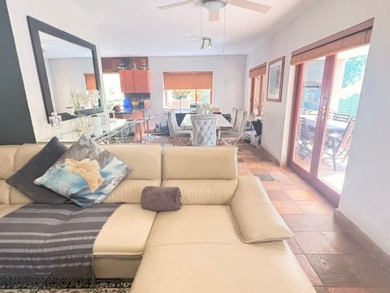 Open-plan living and dining area featuring tiled flooring, a ceiling fan, and large sliding glass doors providing access to the outdoor patio.