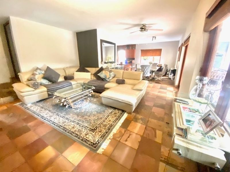 Spacious open-plan living and dining area featuring natural stone tile flooring and a ceiling fan, offering a versatile layout for family living.