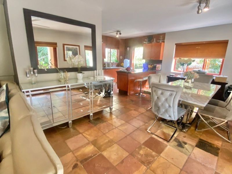 Open plan living and dining area featuring tiled flooring, a kitchen island with breakfast bar, and integrated cabinetry, creating a functional and connected living space.