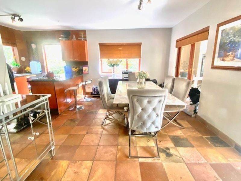 Open-plan kitchen and dining area featuring terracotta floor tiles, wooden cabinetry, and a central kitchen island, offering a functional layout for daily living.