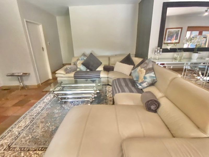 A spacious living room featuring tiled flooring and a large wall-mounted mirror, providing a neutral base for interior design updates.