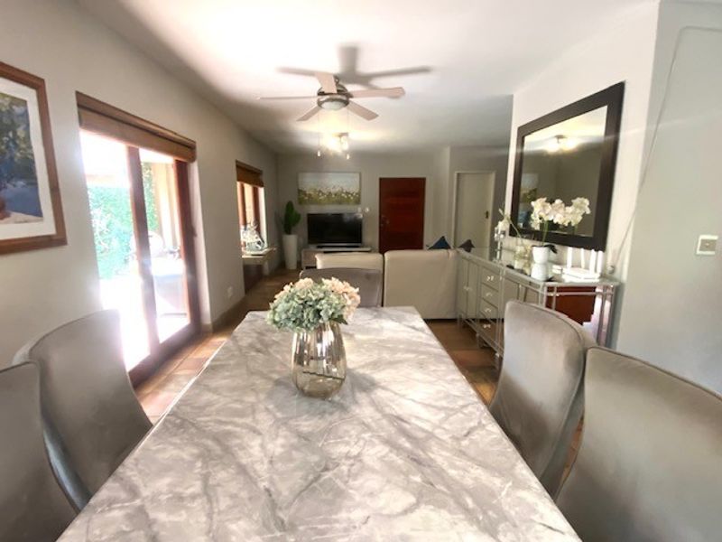 Spacious open-plan living and dining area featuring neutral tones, a ceiling fan, and large sliding glass doors providing access to the outdoor space.