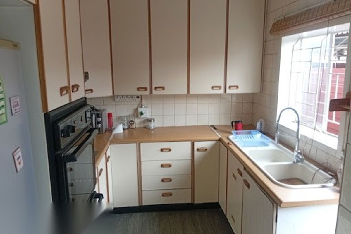 A functional kitchen featuring fitted cabinetry, laminate countertops, a double bowl sink, and a built-in oven with a tiled backsplash.