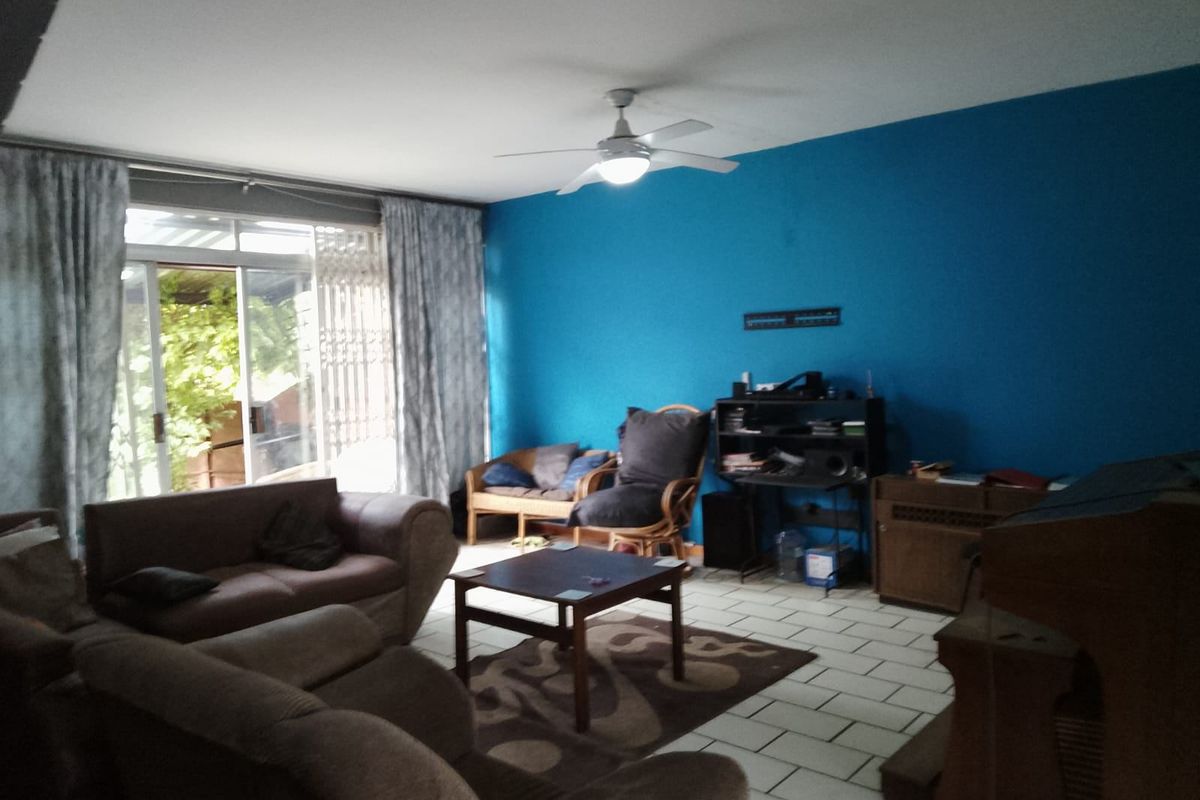 A living room featuring tiled flooring, a ceiling fan, and a sliding glass door providing access to the outdoor area.