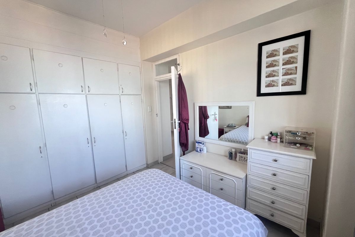 A bedroom featuring extensive built-in white cabinetry, a ceiling fan, and a transom window above the doorway, providing functional storage and classic architectural details.