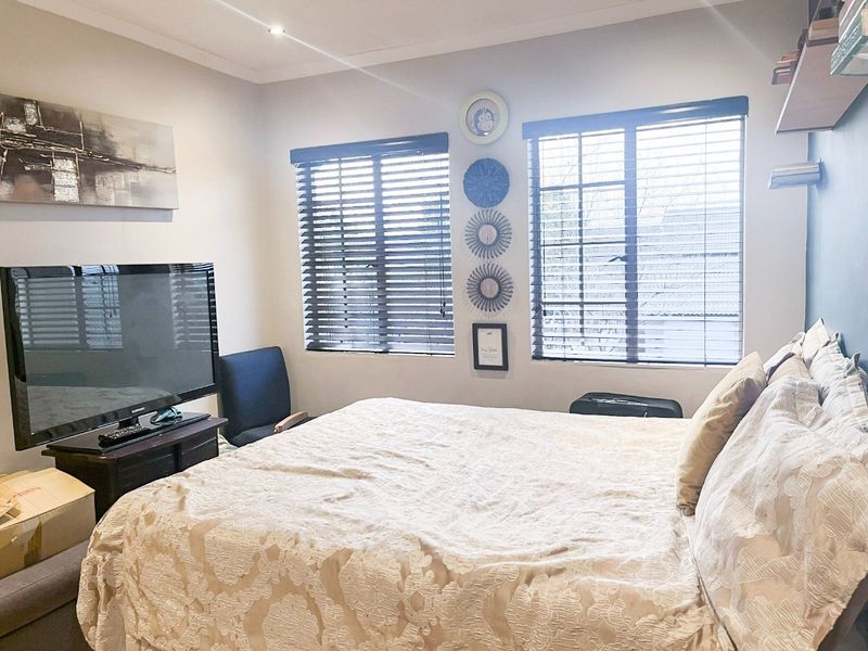 A bedroom featuring neutral walls, recessed downlighting, and dual windows fitted with venetian blinds.