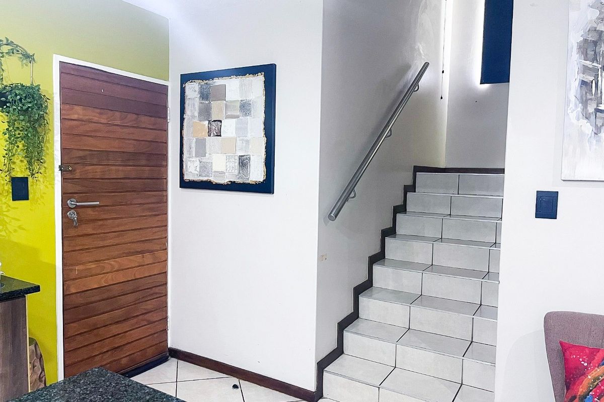 Entrance area featuring a solid wood front door, tiled staircase with a modern stainless steel handrail, and neutral ceramic floor tiling.
