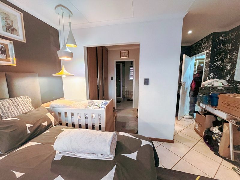 Bedroom featuring built-in cupboards, tiled flooring, and pendant lighting, with direct access to an en-suite bathroom.