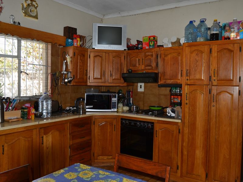 A functional kitchen featuring traditional wooden cabinetry, a built-in oven with gas hob, extractor fan, and tiled backsplash, offering a classic farm-style aesthetic.