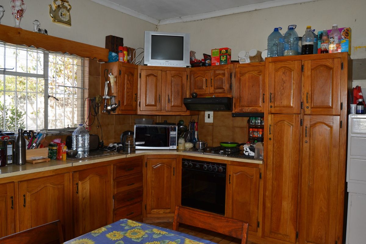 A functional kitchen featuring traditional wooden cabinetry, a built-in oven with gas hob, extractor fan, and tiled backsplash, offering a classic farm-style aesthetic.