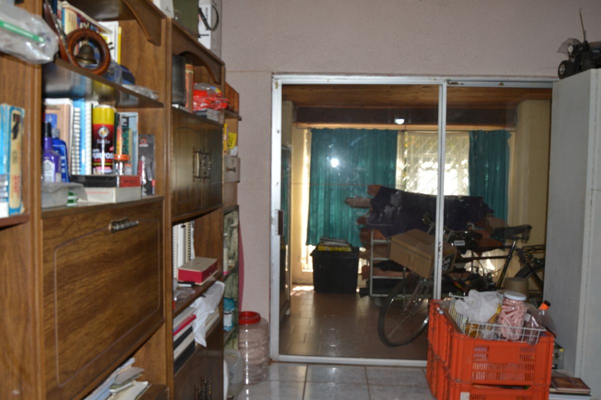 A living area featuring tiled flooring and a sliding glass door leading to an adjacent space with a timber ceiling.