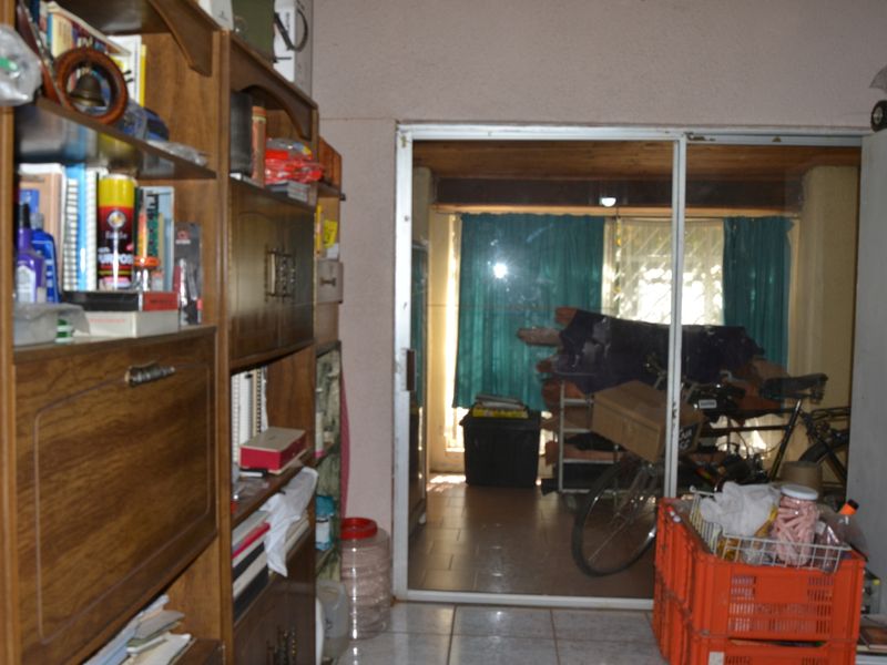 A living area featuring tiled flooring and a sliding glass door leading to an adjacent space with a timber ceiling.