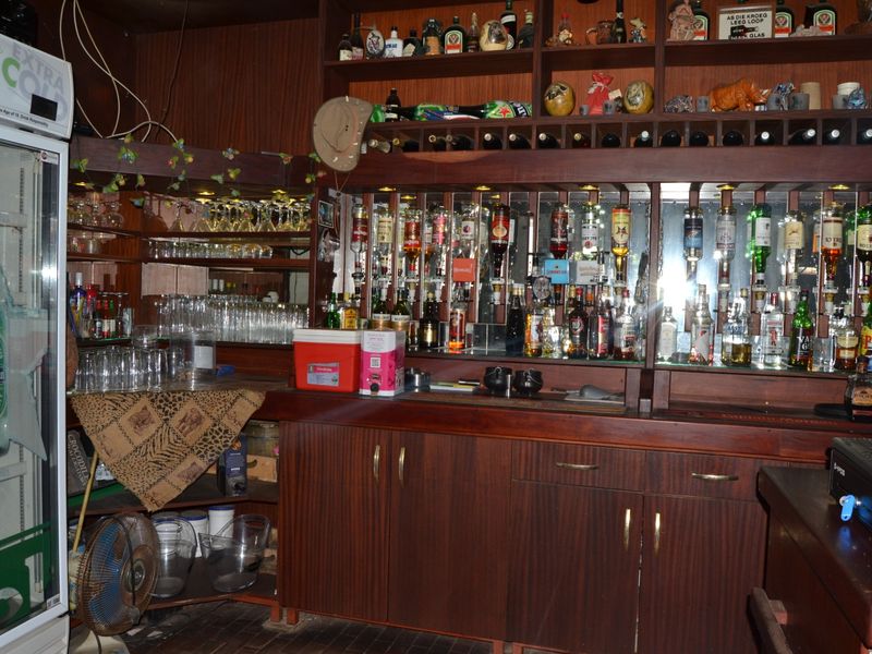 A dedicated bar area featuring custom wooden cabinetry, a mirrored back bar, and integrated shelving for glassware and beverage display.