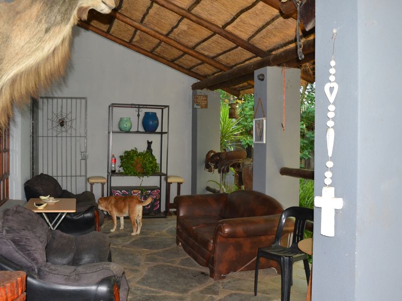 Covered outdoor patio area featuring a rustic thatched roof and natural stone flooring, providing a sheltered space for relaxation.