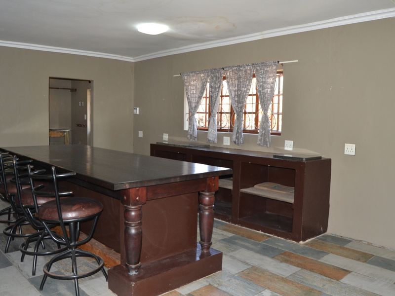 A dedicated bar area featuring a large built-in wooden counter, stone surfaces, and tiled flooring, requiring minor ceiling repairs.
