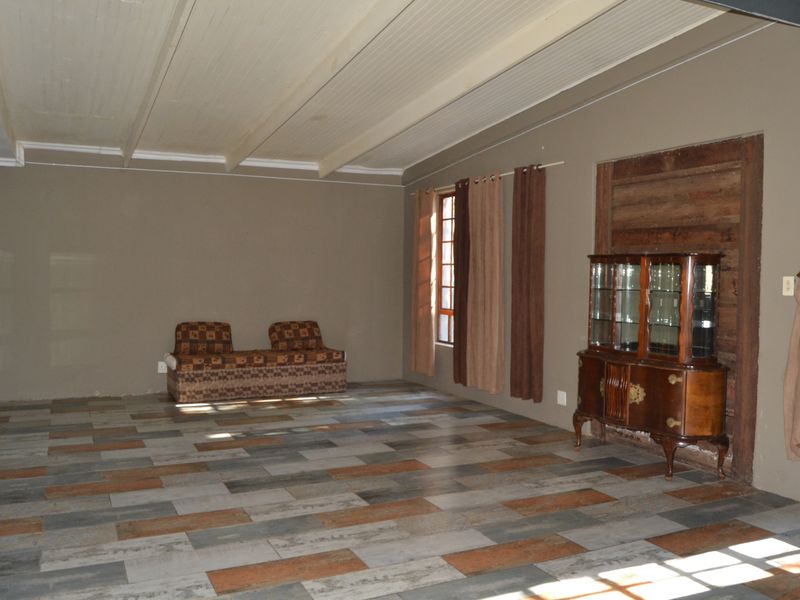 Spacious living area featuring modern timber-look tile flooring and a traditional beaded timber ceiling, offering a neutral canvas for interior design updates.
