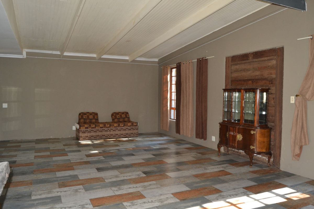Spacious living area featuring modern timber-look tile flooring and a traditional beaded timber ceiling, offering a neutral canvas for interior design updates.