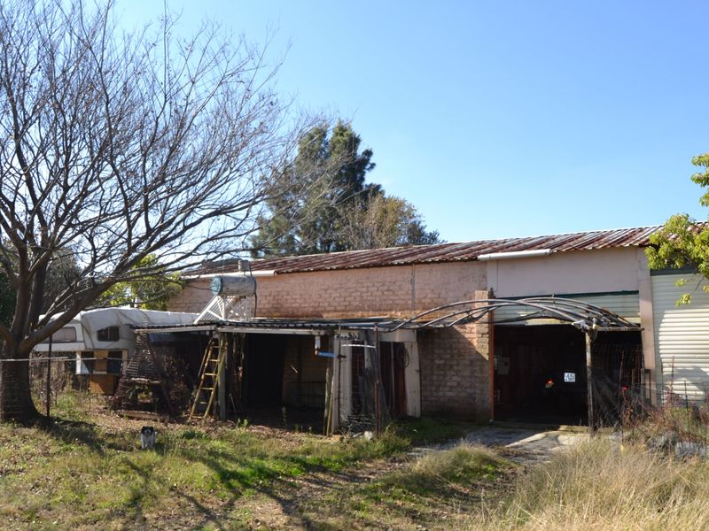 Exterior view of a residential property featuring a brick structure with a corrugated metal roof, integrated garage, and solar water heating system.