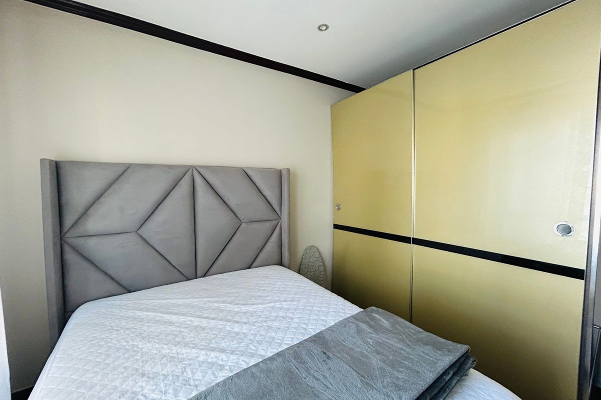 A bedroom featuring a large built-in wardrobe with gold-toned sliding doors and recessed ceiling lighting.