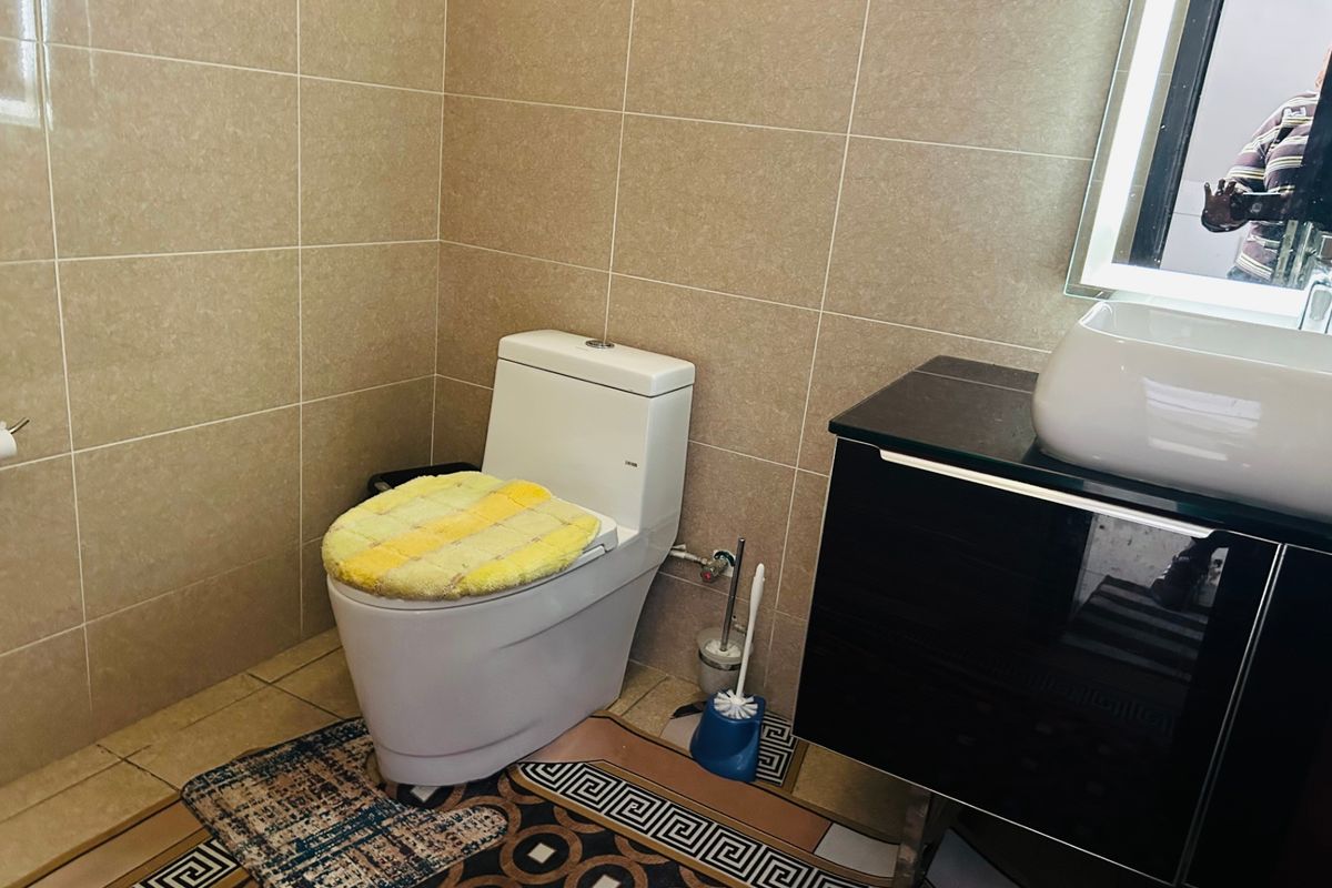 A modern bathroom featuring a sleek wall-mounted vanity with a vessel sink, backlit mirror, and neutral wall tiling.